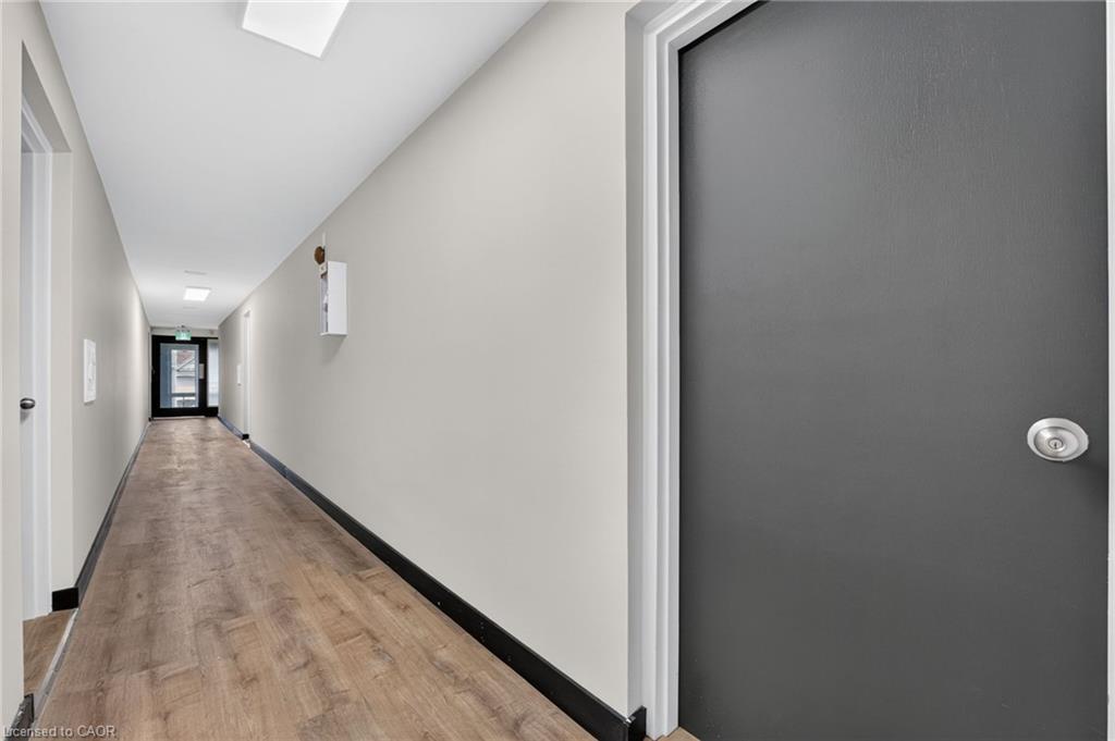 Empty hallway with wood-look flooring and a dark gray door in the foreground.