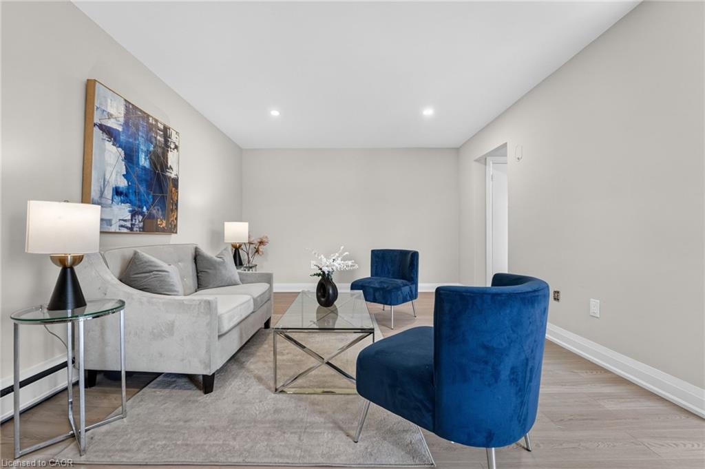 Staged living room with a gray sofa, blue velvet chairs, and glass coffee table.