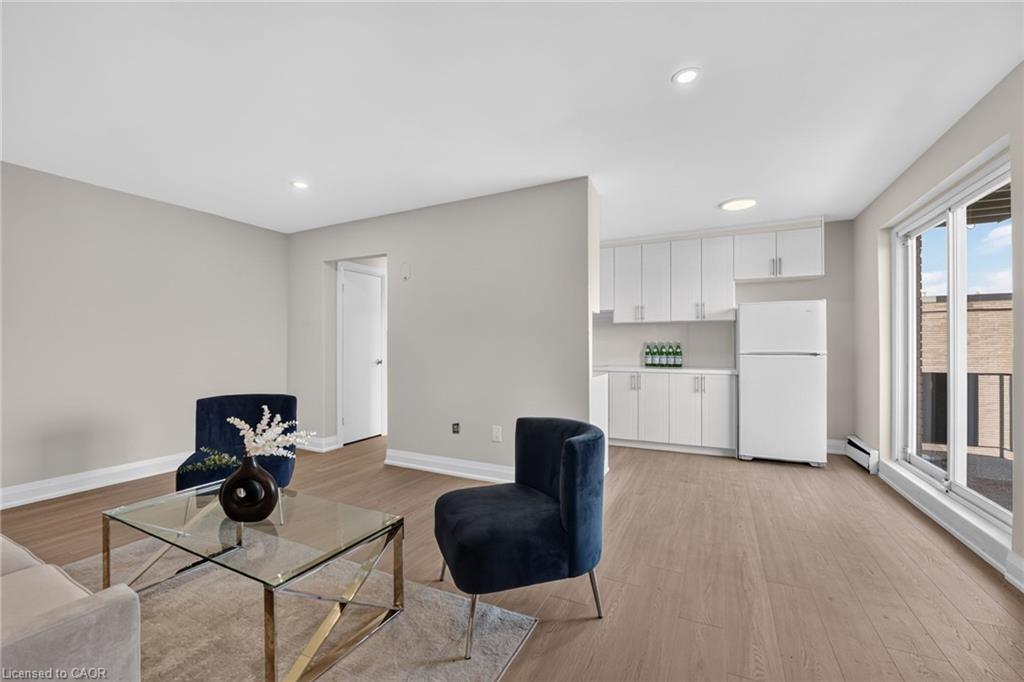 Staged living room with a compact white kitchen and sliding glass doors to a balcony.