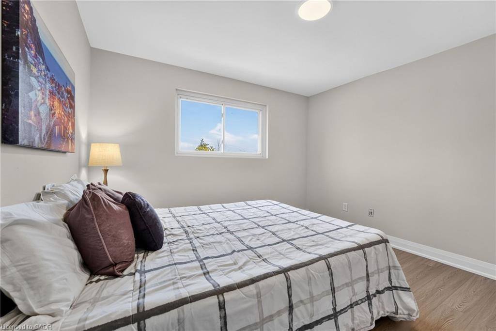 Bedroom with a gray plaid bedspread, mauve pillows, and a small window.