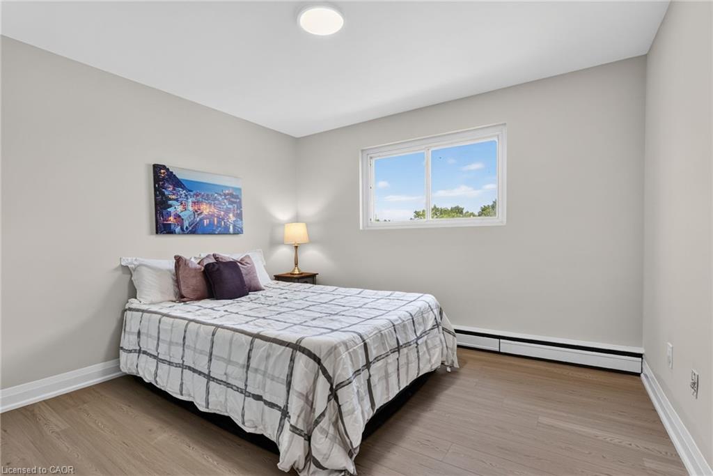 Staged bedroom with gray plaid bedding, wood-look flooring, and a high window.