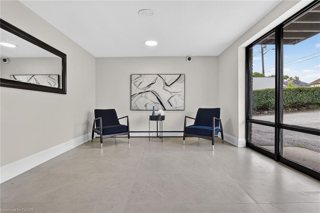 Lobby sitting area with two navy chairs and full-height glass doors overlooking a hedge.