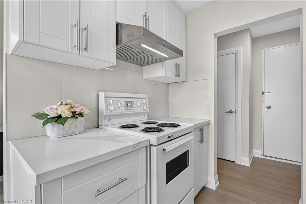 Compact kitchen with white cabinetry, an electric range, and a stainless-steel range hood.