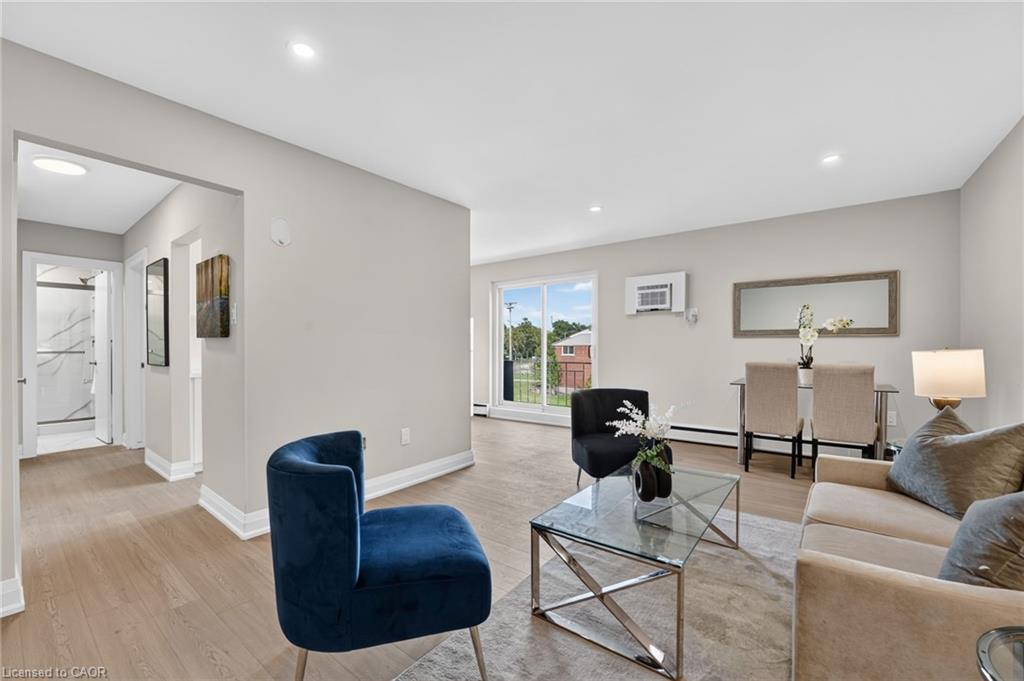 Open living and dining area with a navy accent chair, glass coffee table, and window.