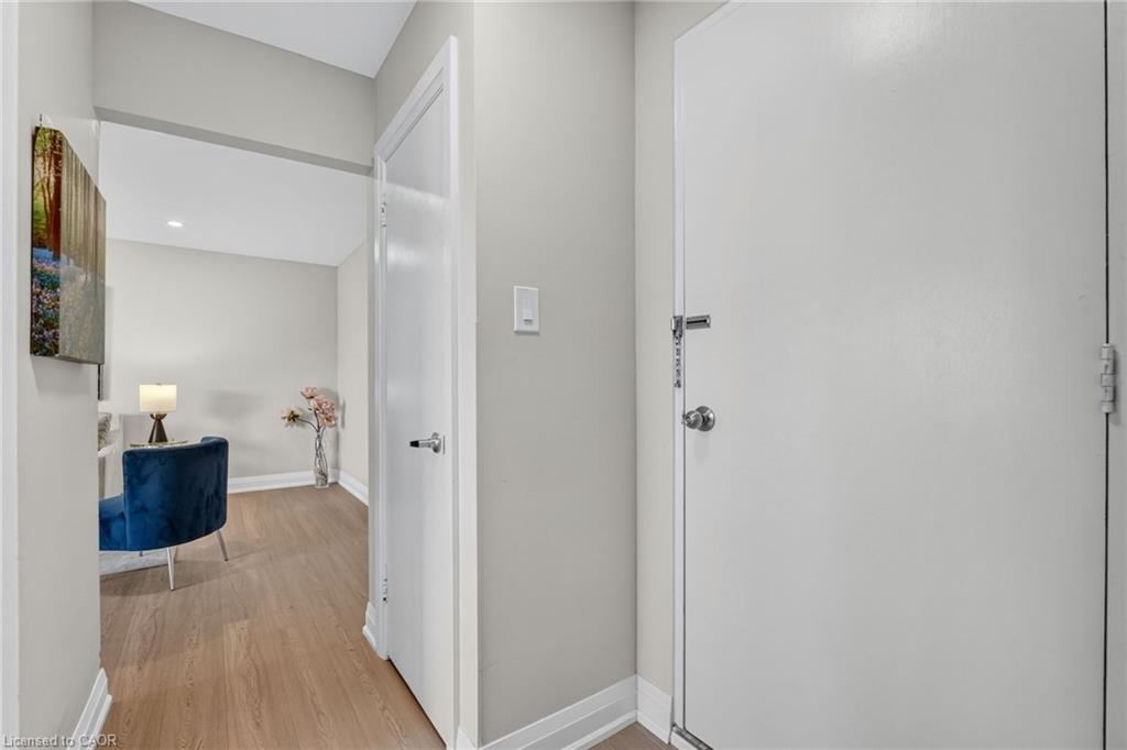 Home entryway with white doors, wood-look flooring, and a blue chair in the adjoining room.