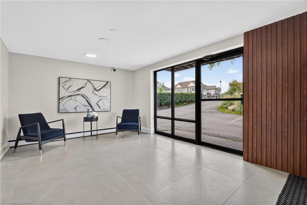Building lobby with navy chairs, tiled floors, and glass doors beside a wood-slat wall.
