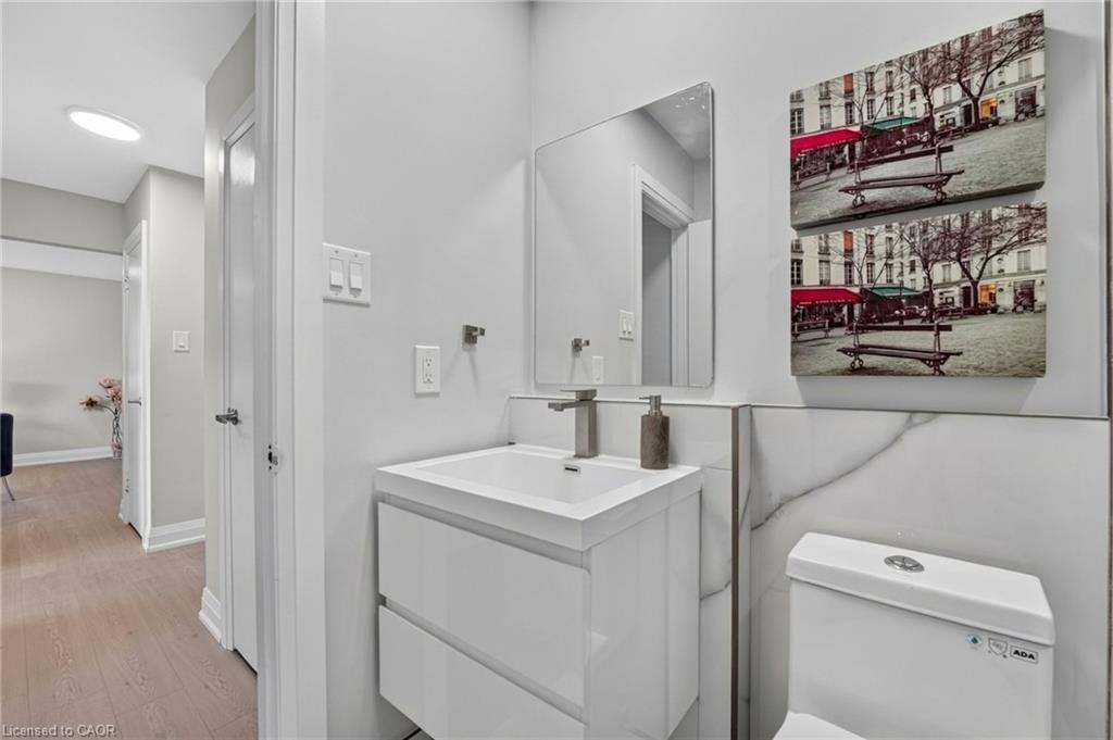 Modern bathroom with a white vanity, marble-look wall panels and two stacked framed prints.