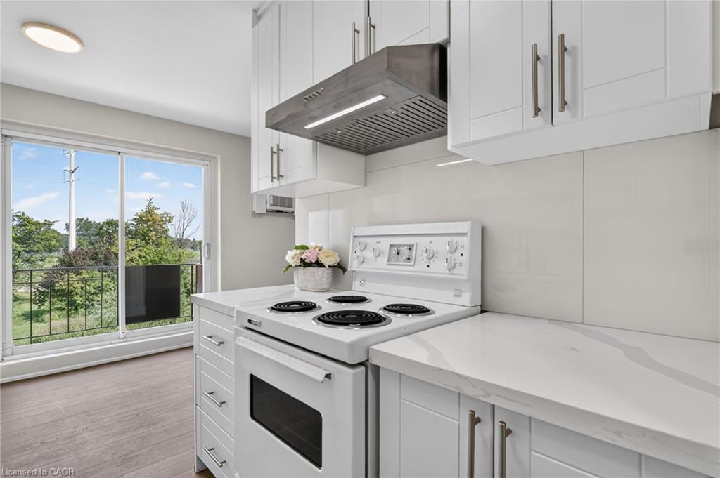 Bright white kitchen with an electric stove and sliding glass door opening to a balcony.