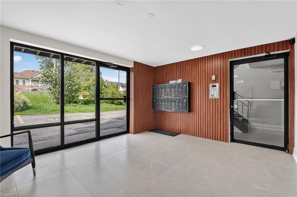 Lobby with wall-mounted mailboxes, wood-paneled wall, and large windows overlooking greenery.