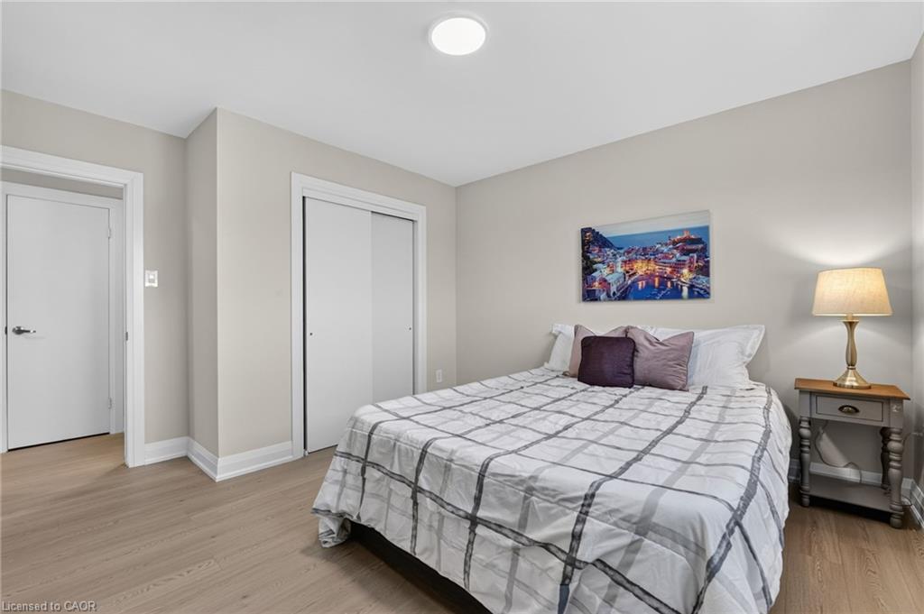 Bedroom with a gray grid-patterned duvet, sliding-door closet, and bedside table with a lamp.