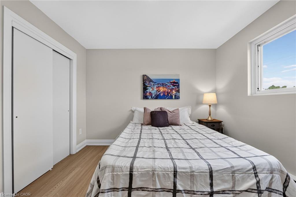 Staged bedroom with a plaid-covered bed, bedside lamp, sliding-door closet, and window.