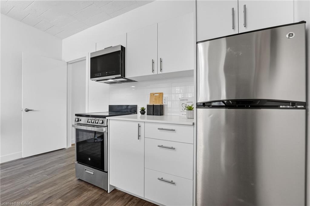 Kitchen with white cabinetry, stainless-steel appliances, and gray wood-look flooring.