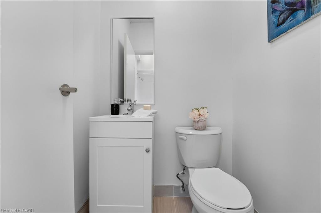 Bathroom with a white vanity, rectangular mirror, toilet, and vase of flowers.