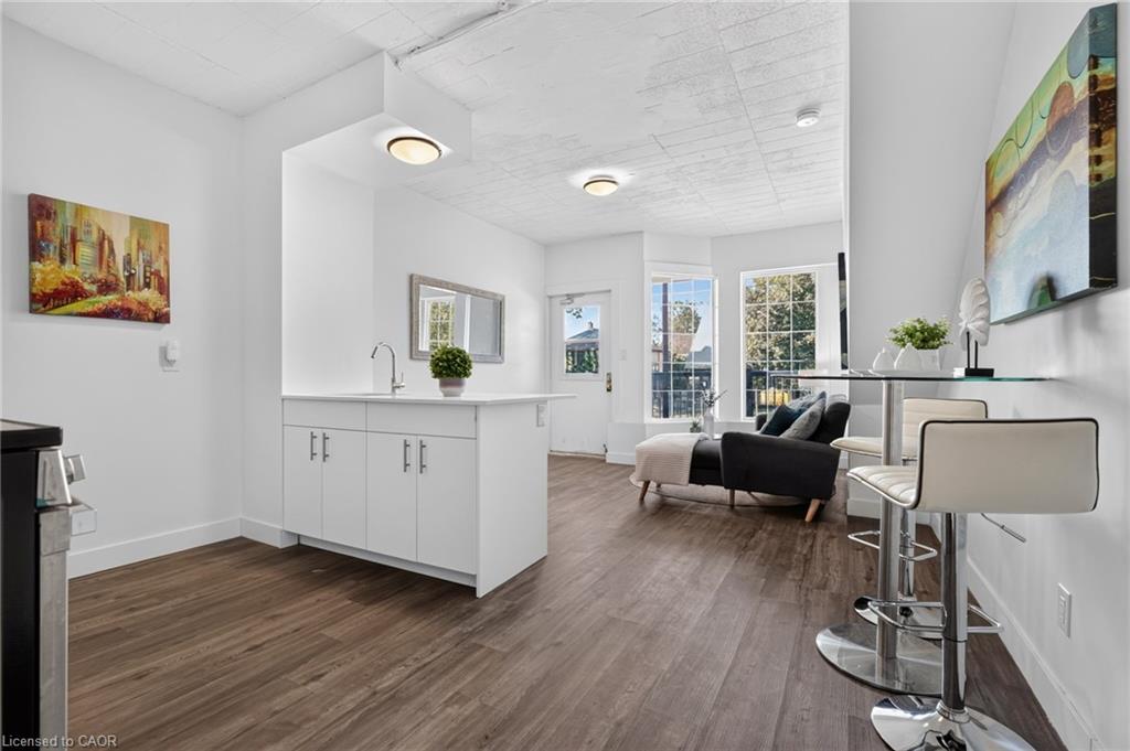 Open-plan kitchen and living area with a white island, bar seating, and large windows.