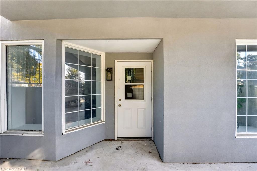 Recessed front entry with a white door and large windows in gray exterior walls.