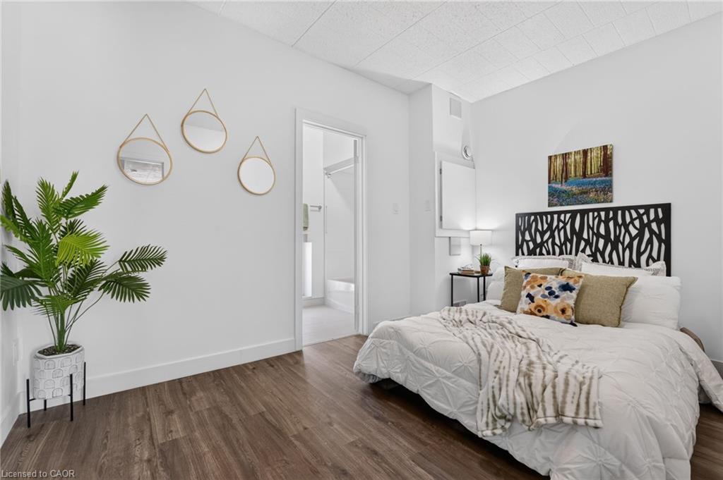Staged bedroom with white bedding, a black patterned headboard, round mirrors, and a potted palm.