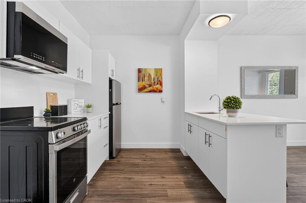 Modern kitchen with white cabinets, stainless-steel appliances, and a white island with sink.