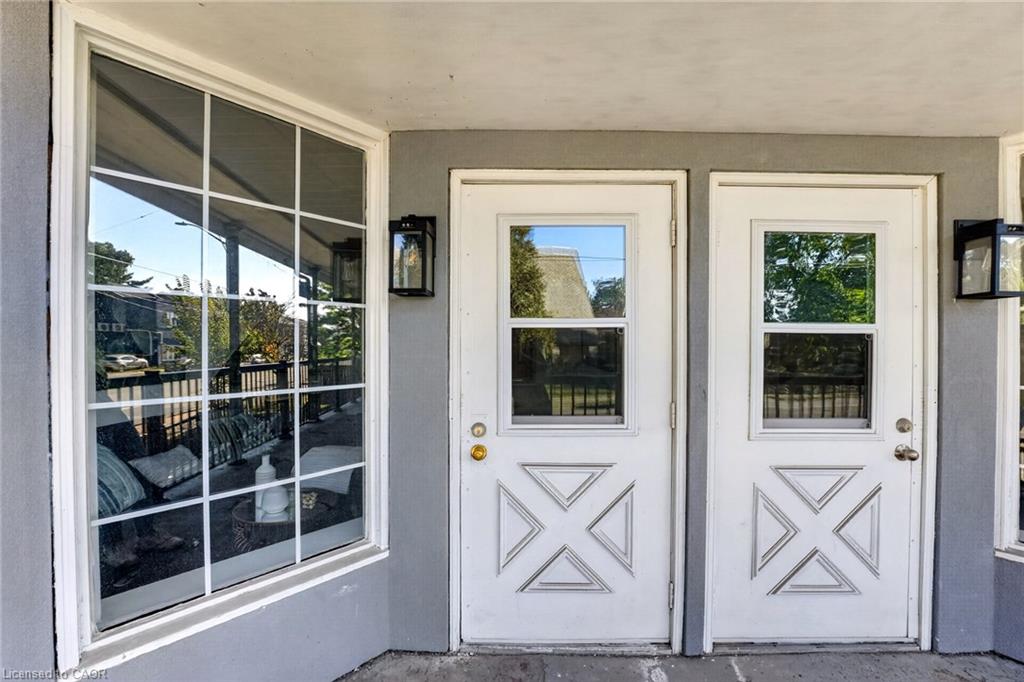 Covered entrance with two white geometric-panel doors beside a large divided-pane window.