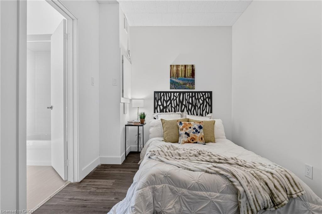 Bedroom with a white bed, patterned black headboard, and open doorway to a bathroom.