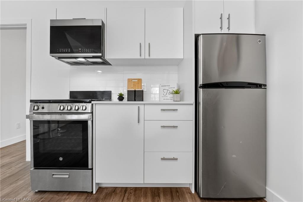 Kitchen with white cabinetry, stainless steel appliances, and wood-look flooring.