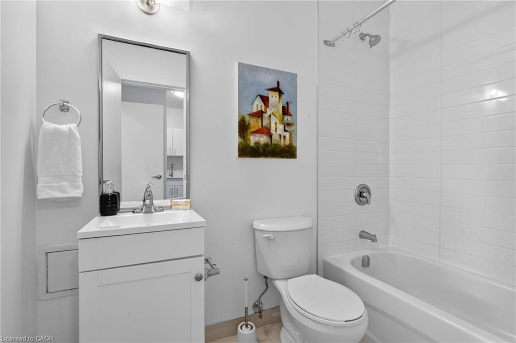 Bathroom with a white vanity, toilet, and bathtub with a tiled shower surround.