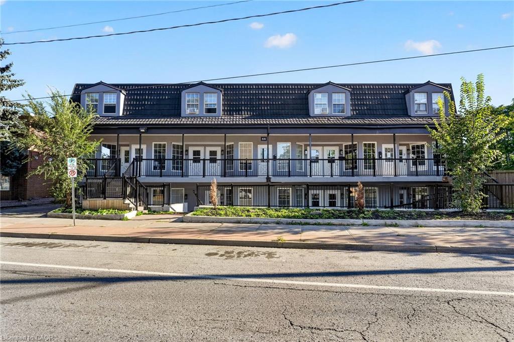 Multi-unit building with a dark mansard roof, dormer windows and long covered balconies.