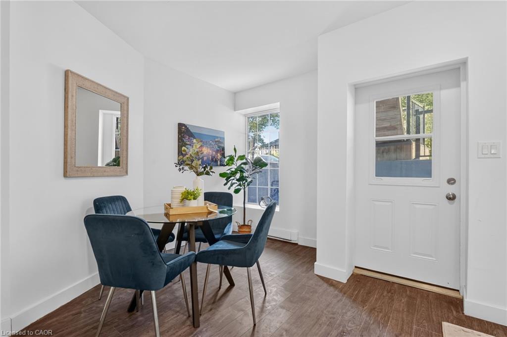 Dining area with a round table, blue chairs, wood-look floors, and a windowed front door.