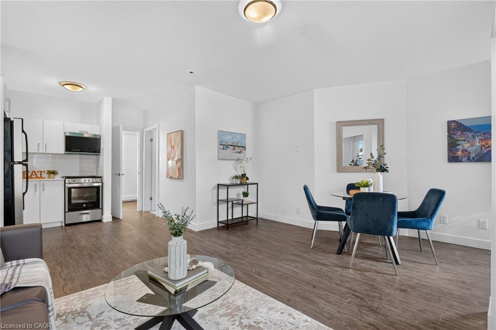 Open-plan living and dining area with a compact white kitchen and blue chairs.