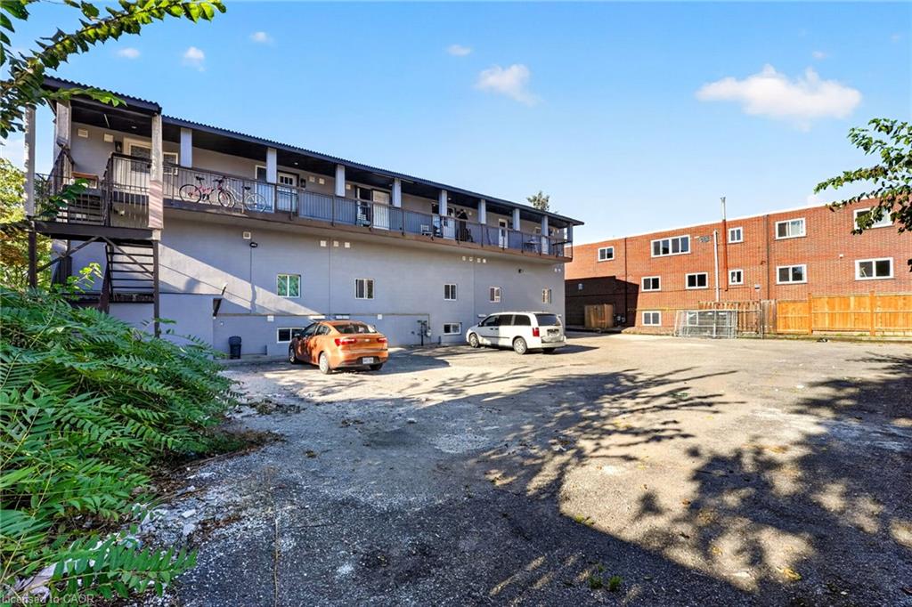 Two-story apartment building with a long balcony overlooking a paved parking lot.