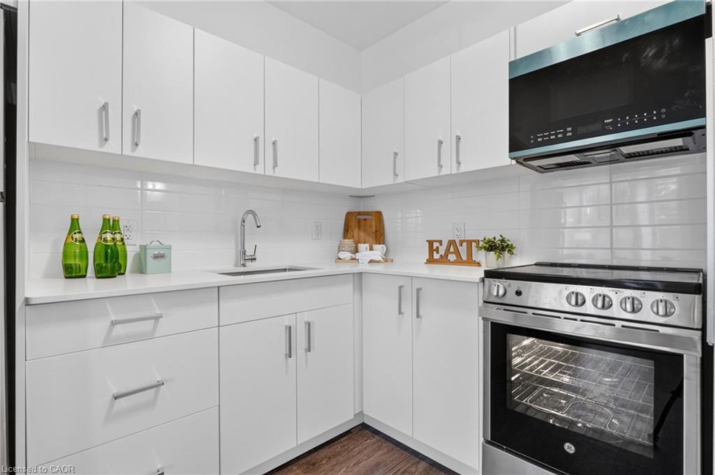 White kitchen with stainless-steel range, built-in microwave, and corner sink.