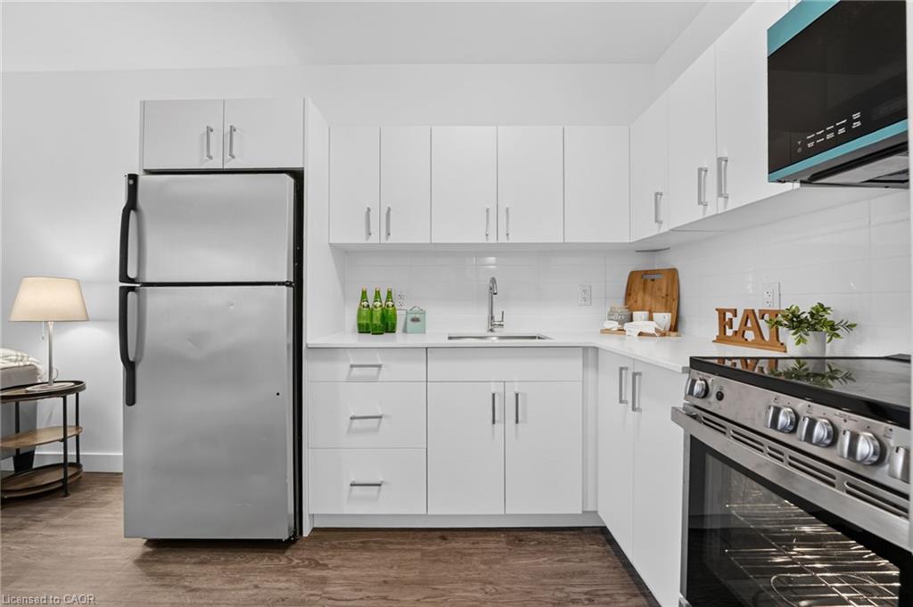 Staged kitchen with white cabinetry, stainless steel appliances, and a small lamp beside the refrigerator.