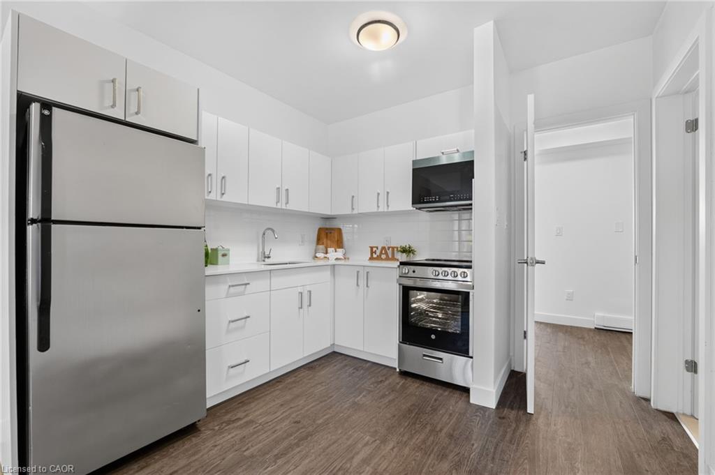 Kitchen with white cabinets, stainless steel appliances, and an open doorway to the adjoining room.