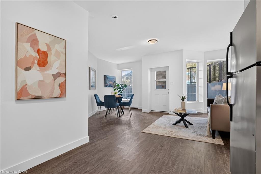 Open-plan living and dining area with blue dining chairs, dark wood floors, and a glass coffee table.