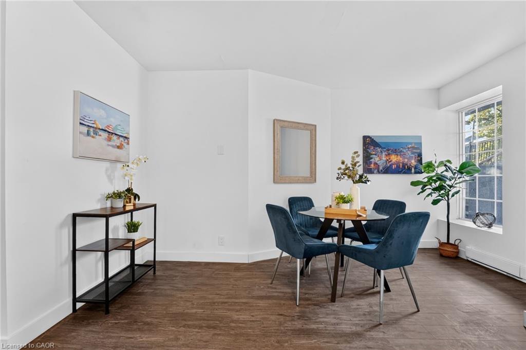 Dining room with a round table, blue chairs, wood-look floors, and a large window.