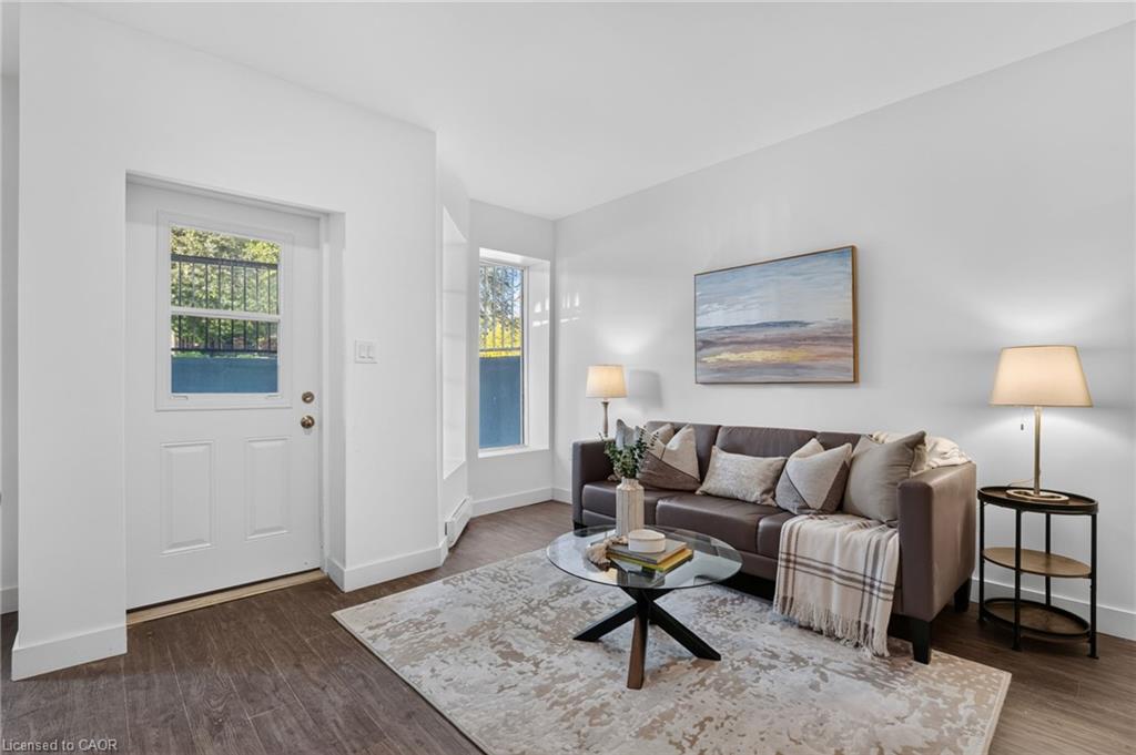 Staged living room with a gray sectional, glass coffee table, and white entry door.