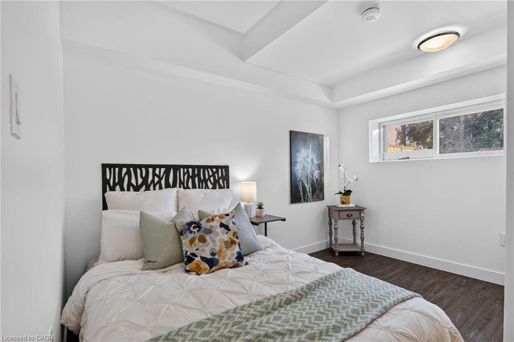 Staged bedroom with a white quilted bed, colorful pillows, and a high horizontal window.