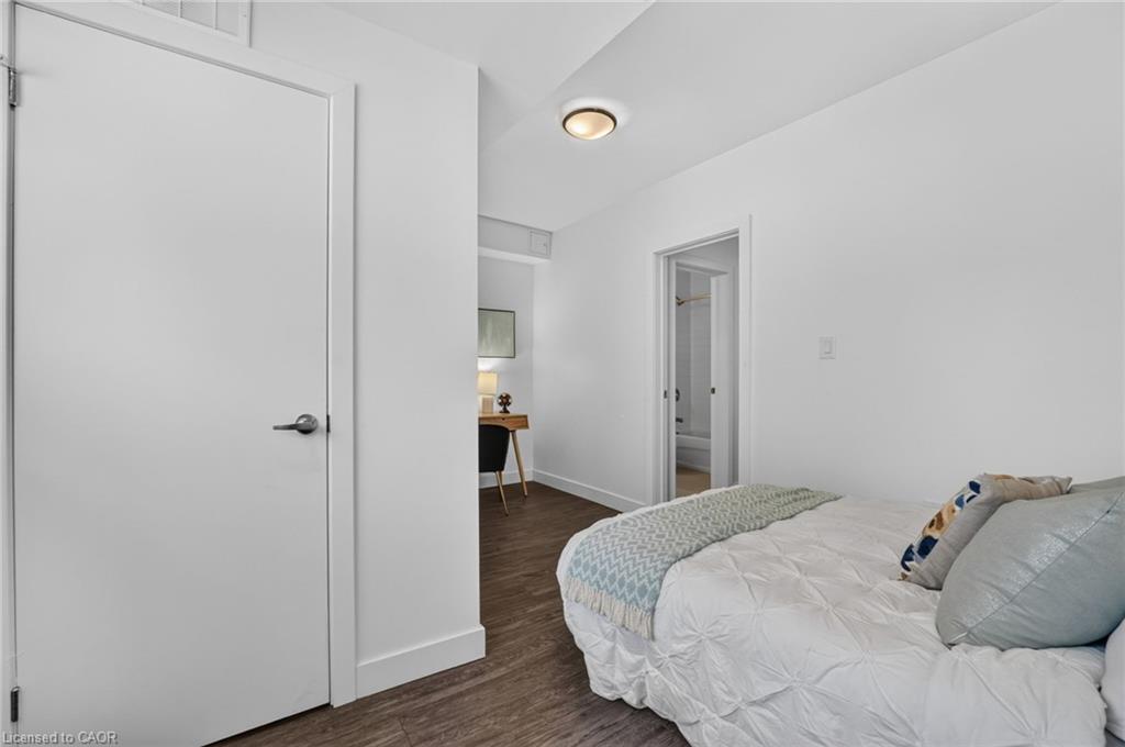 Bedroom with a white bed, dark wood flooring, and an open doorway to the bathroom.