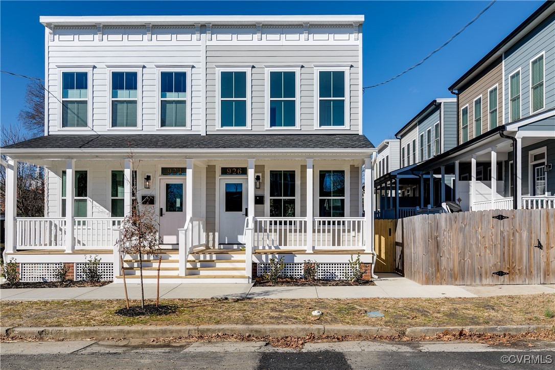 Two attached white homes with matching covered porches and a wooden privacy fence.