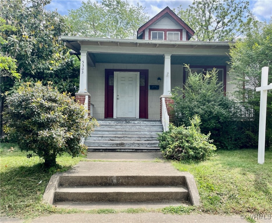 House with a covered porch, red trim, white front door, and broad steps.