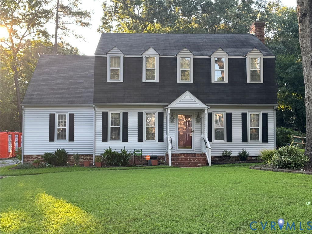 White two-story house with dark shingles, black shutters, and a broad green lawn.