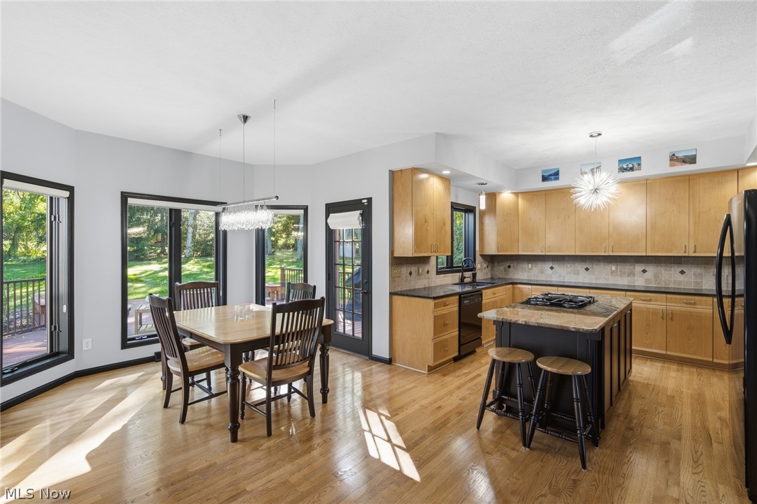 Kitchen and dining area with a central island, wood cabinetry, and windows overlooking the yard.
