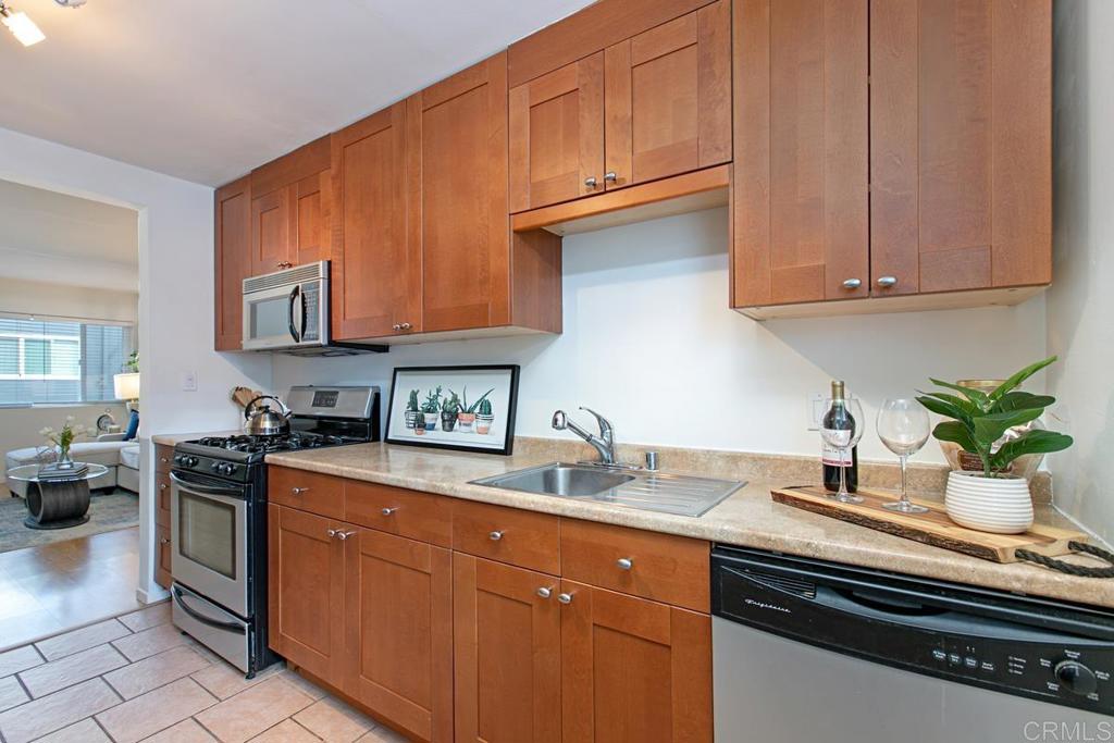 Kitchen with warm wood cabinets, stainless appliances, and a sink beneath a framed print.