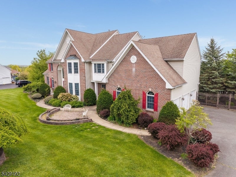 Brick home with red shutters, landscaped garden beds, and a curved lawn.
