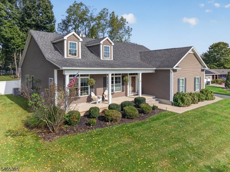Brown two-story home with front dormers, a covered porch, and landscaped lawn.