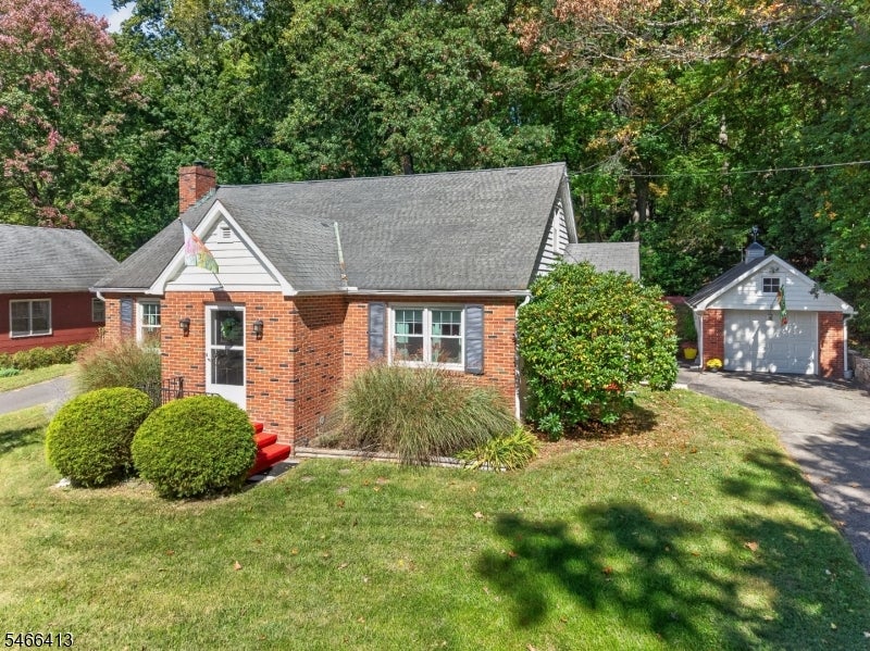 Red brick home with front shrubs and a detached garage beside the driveway.