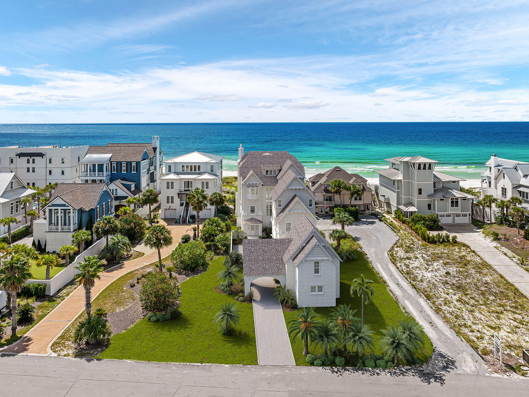 Aerial view of coastal homes beside turquoise ocean and a sandy beach.