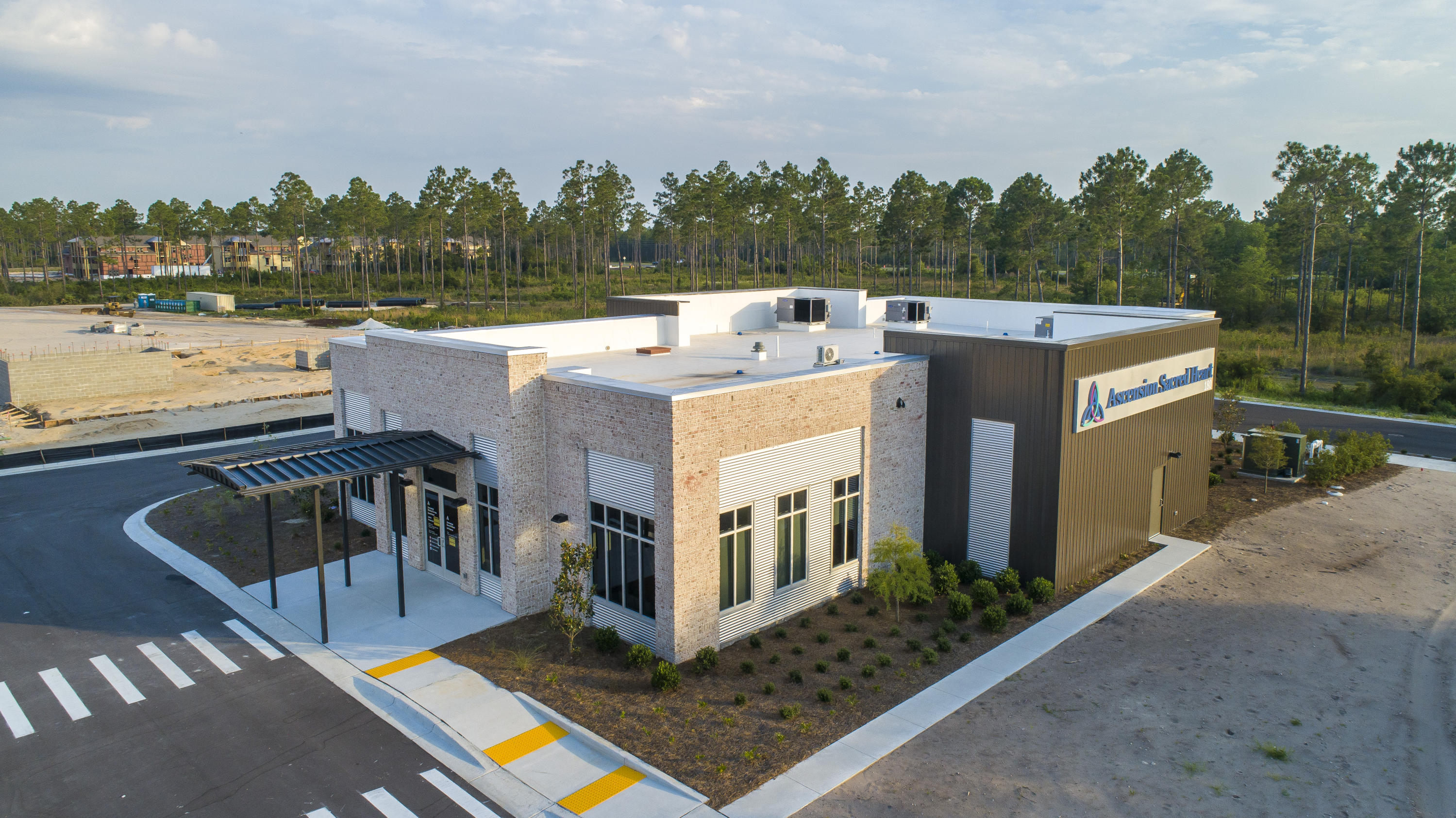 Modern brick and metal medical building with a covered entrance and Ascension Sacred Heart sign.