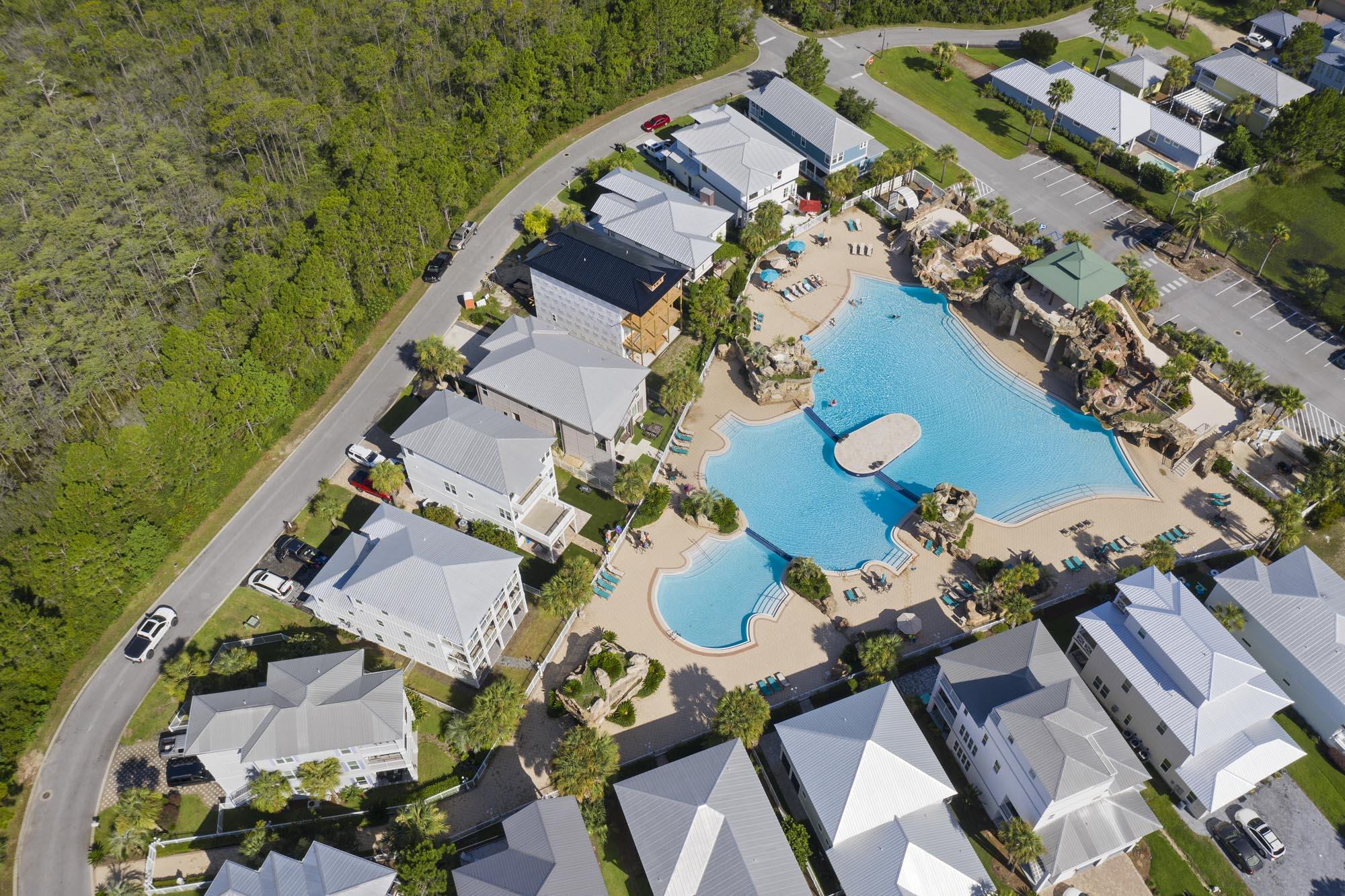 Aerial view of a neighborhood pool surrounded by homes and wooded land.