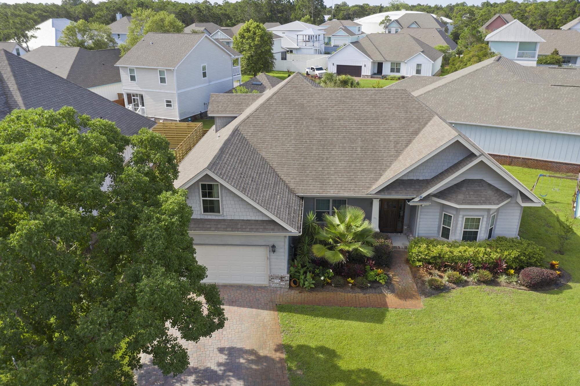 Gray home with a multi-gabled roof, landscaped entrance, attached garage, and broad front lawn.