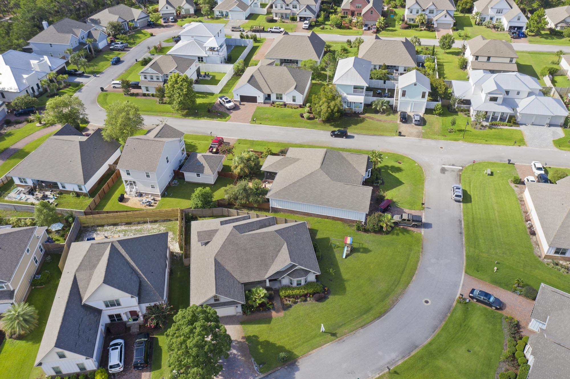 Aerial view of a residential neighborhood with detached homes, green lawns, and a curving street.